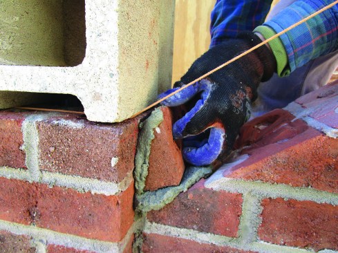After laying the field bricks for the side wall, the author began the final course of rowlocks (bricks laid on edge). He ripped the bottom brick at 29 degrees for the pitch of the slope.