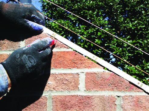 Using a brick-spacing ruler, he laid out even spacing of the rowlocks.