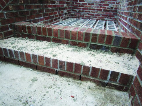 A rowlock course finished that step, leaving the open weep holes, and he spread a layer of sand to protect the step from mortar droppings as he worked his way to the top.