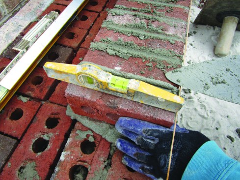 As the author laid each rowlock brick to the line, he set his torpedo level on top to ensure that it was pitched the same as the end bricks.