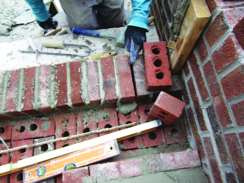Every few bricks, he checked the spacing with a brick-spacing ruler. By adjusting the thickness of the joints, he fit the final brick perfectly.