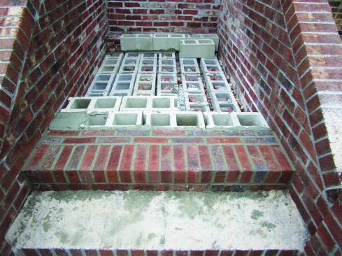 After finishing the rowlock course at the front of each step, he laid two courses of rowlock stretchers behind the front row (33). These bricks ran perpendicular to the front row, with the joints between bricks in each of the two rows offset by half of a brick length. Behind the steps, he filled in with blocks cut to 6 1/4 inches high. With the mortar joint, the blocks came up even with the brick step at the front.
