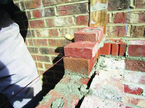 It slips around the twine, and while the weight of a brick holds it precisely in place.
