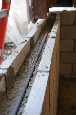 After filling the bond beam blocks partially with wet concrete, the crew installed horizontal rebar. 