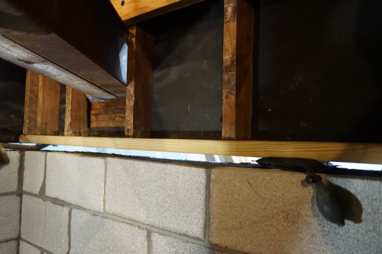 With the block wall finished, the crew replaced the old mudsills with new treated sill stock, using inflatable shims and heavy-duty pry bars to hold the new plates tight against the bottoms of the existing studs for fastening.