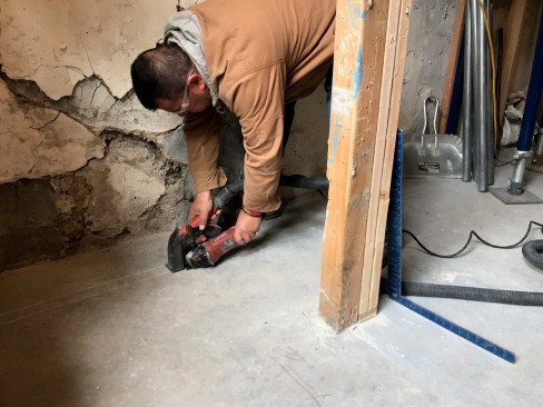 Before assembling the support for the needle beams that carried the wieght of the wall, a crew member scored the concrete slab for the new footing with a concrete saw.