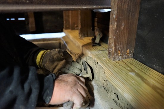 The crew filled the gap between the block foundation and the sills with high-strength non-shrink grout, forcing it under the sill from the inside with a margin trowel.