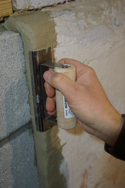 The crew used an edging trowel to smooth the grout along the top of the foundation and to smooth the seam between the existing foundation and the new block foundation. 