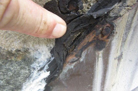 The flashings along the back, sides, and front are nailed to the face of the stone (the peeled-back caulk reveals a nail head). Through-wall flashing was not installed—an all-too-common defect the author encounters in the area where he works (see JLC May ‘23, “Getting to the Bottom of a Stone-Veneer Leak”).
