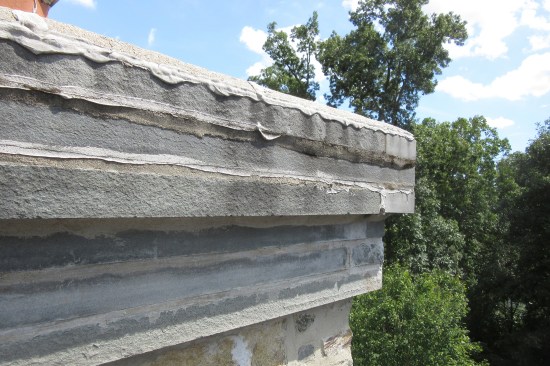Caulked mortar joints of the corbeled out 1-inch-thick bluestone cap. Multiple colors of caulking on the chimney crown, veneer, and base flashings suggest frustrated attempts over the years trying to stop leaks.
