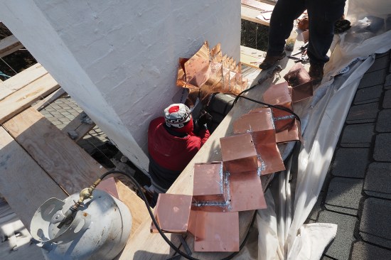 The stepped, 16-ounce copper through-flashings are fabricated and soldered on site.