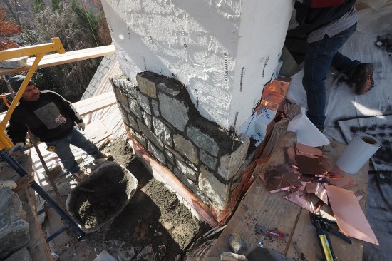 The stone veneer is reapplied, building the chimney out to its original 44-by-66‑inch dimension. A new chimney cap was later installed by the mason.