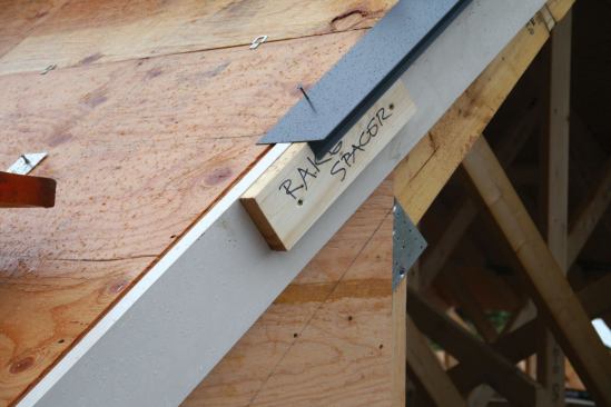 Since roofline trim would be installed when the house was clapboarded, I tacked on spacer blocks that simulated the width of the rake trim and eaves fascia before running the drip edge, which was nailed in place as we shingled.