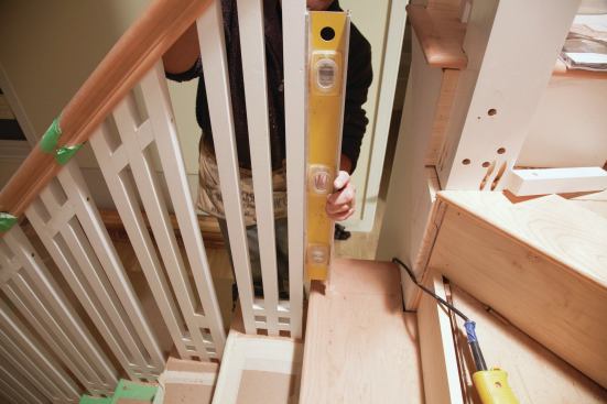 After scribing and trimming to adjust the fit of the baluster against the tread, the author plumbed the assembly in position against the railing and marked the top ends where they intersected the bottom of the handrail. Before cutting them, 3/8 inch was added to allow for the plow in the underside of the railing. The location of the angled top cross-blocks was also marked to ensure alignment between balusters. With temporary spacers placed between balusters to keep them parallel, the end angles were cut on a chop saw. (Also see photo 21.)