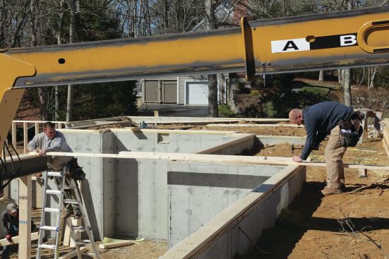 Then we make sure it's parallel to the front wall. Once it's level and braced to the exterior wall with a 2x6, we measure from the concrete to the bottom of the beam. With this number we can make a triple 2x6 column to carry one end of the beam.