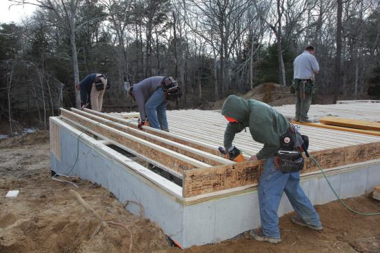 Three crew members begin rolling up the I-joists and nailing them off at our three attachment points.