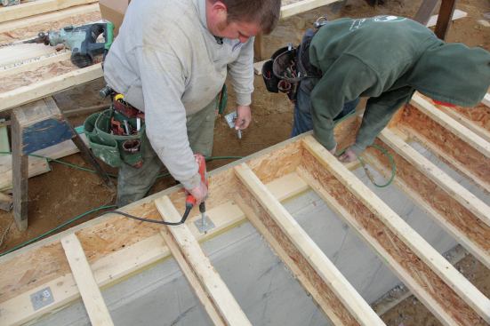 A second cleans out the hole using an air hose.