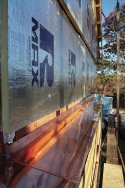 Copper flashing covers a pitched shelf above the wall trusses, and rigid foam covers the upper walls of the house.
