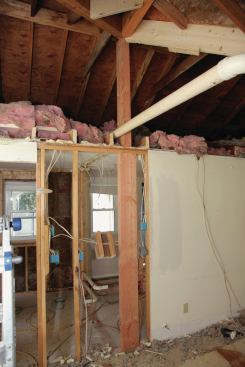 The framers inserted a post to support the existing triple 2x8 valley as well as the new structural ridge. They continued the post down through the wall framing below, and down into the crawlspace, where we poured a footing to pick up the point load. The framers also removed the section of original roof framing that continued under the roof of the addition; this exposed the entire length of the valley from below.
