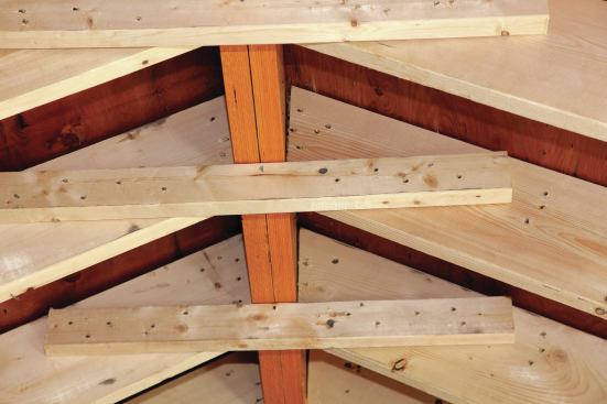 Jack rafters were either sistered or added as needed along both valleys. To deal with uplift issues without opening up the roof, 2x4 collar ties were used to join each pair of rafters. The ties gave the ceiling a flat section at the top, but the clients were fine with that compromise, and it gave the electricians a level place to mount the ceiling fan.