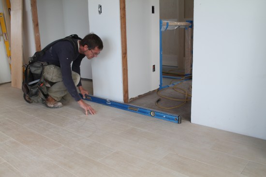 Installation starts with a check of the openings. Here floor level is checked between two adjacent door openings. If it is off, the head casings will not align without some adjustment.