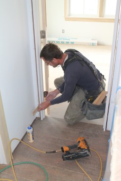 Slip shims behind the jamb just below the bottom hinge, and adjust the shims until the gap between the head jamb and door slab is perfectly even.