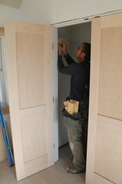 Insert shims above the top hinges on both sides to center the door in the opening, and shoot just one nail through the shims to allow for adjustment.