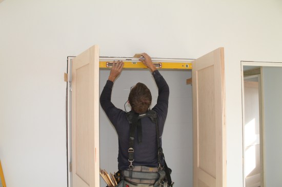 Using a level as a straightedge, shim the  head jamb until it is perfectly straight. Don't nail through the shims, they will be removed when the casing is installed to hold the jamb straight.