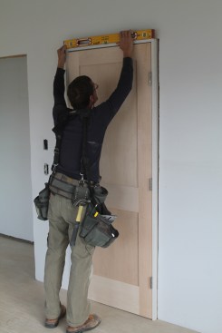 With the temporary fasteners still in place, set the door in the opeing and check the head jamb for level. If it's not dead on, take the door out and make the adjusting cut.