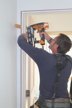 If the head is level, release the temporary fasteners and secure the hinge jamb just above the top hinge with shims and a nail.