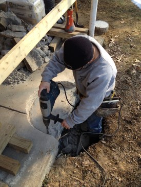 Working with an impact hammer, the author chips away the concrete slab where the footing will be located.