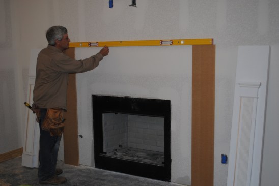 Before securing attachment boards to the wall, he levels between them.