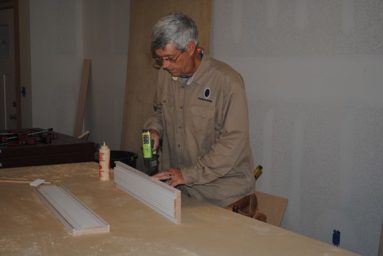 He adds small strips to the sides of the reeded boards.