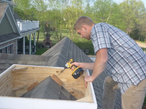 After setting the base in place on the roof, author beds attachment blocks in silicone and screws them into the roof. 