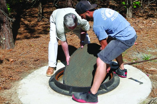 A manhole cover and sleeve provide access to the well pit. Removing the cast-iron cover requires crowbars and two strong adults.