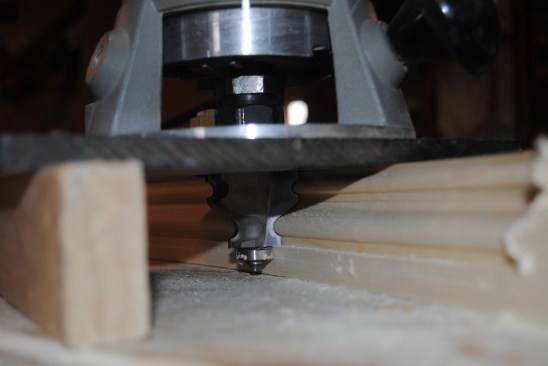 The panel molding for the curved top had to be profiled on edge, so the author used a bearing-guided bit in a router to do the cutting.