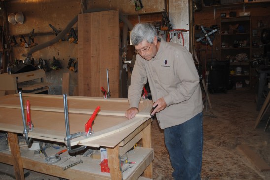 The author clamps each piece in place as it is cut to fit. Here he uses a hand plane to shape the top end of the center stile where it joins the curved rail. 