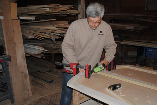 A clamp draws the curved molding into position where it can be glued and nailed into place.