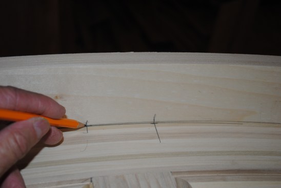 With the top positioned, the author marks registration lines on the curved rail to align it with the stiles of the pack panel.
