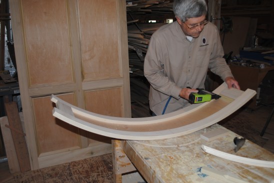 After flipping the curved top panel over, the author begins attaching the panel molding. Note that the center stile is still missing.