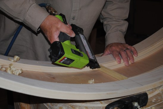 The author nails in the final piece to complete the molding for the first side of the curved top.