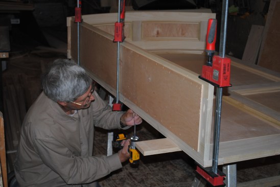 After aligning the side panels with the layout lines made earlier and clamping them in place, the author screws them to the back panel.