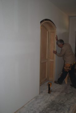 After removing the temporary OSB spreader from the bottom, the author slides the completed niche into the prepared hole in the wall.