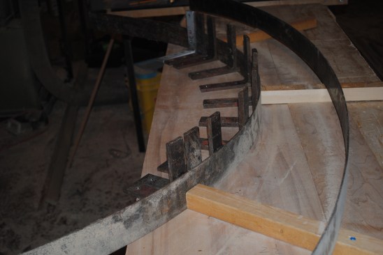 Because the top rail and molding for the back panel have to be glued on the flat, the author screws 2x2 blocks to the bench top to raise the level of the glue up. The raised surface centers the clamping pressure on the pieces being laminated and it minimizes the surface area that gets glued by the squeeze out.