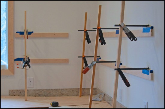The steel dowels were aligned and leveled using plywood strips mounted horizontally on the wall and vertical support sticks. The steel dowels were set with two-part West System Six10 epoxy adhesive, spring-clamped to the support sticks, and obsessively rechecked for level.
