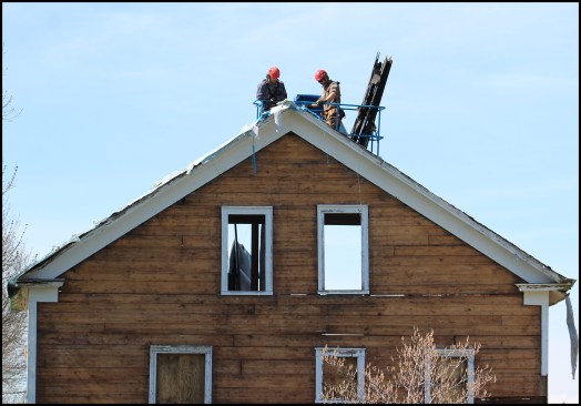 Although the roof was covered by four layers of asphalt shingles, two tarps and two layers of underlayment paper, it still leaked, causing the bulk of the damage to the home’s structure. Here, the roof sheathing and shingles are removed in small sections from the lift.