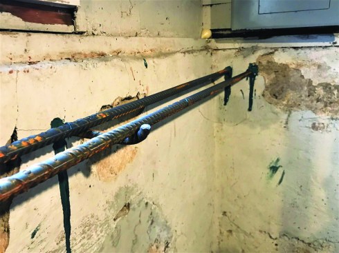 Then the crew used high-strength epoxy to attach two lengths of rebar at one end of the wall. Short lengths of rebar drilled and epoxied into the foundation wall provide support for the rebar along its length.