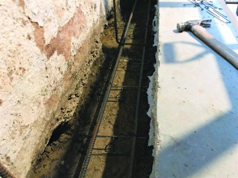 In the footing trench, lengths of rebar were set on chairs pinned to the base of the footing. One of the 2-foot voids that was dug out under the existing foundation every 2 feet is visible in the foreground.