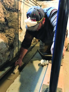 The concrete for the footing extended into the voids under the existing wall to support it. The crew mixed and poured concrete for the footing from bags, troweling the top for a smooth surface.