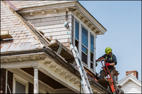 Complex roofs with multiple dormers are common, requiring some carpentry work. Here, author Jeff Spencer shingles a dormer side wall after installing new copper step and apron flashing.